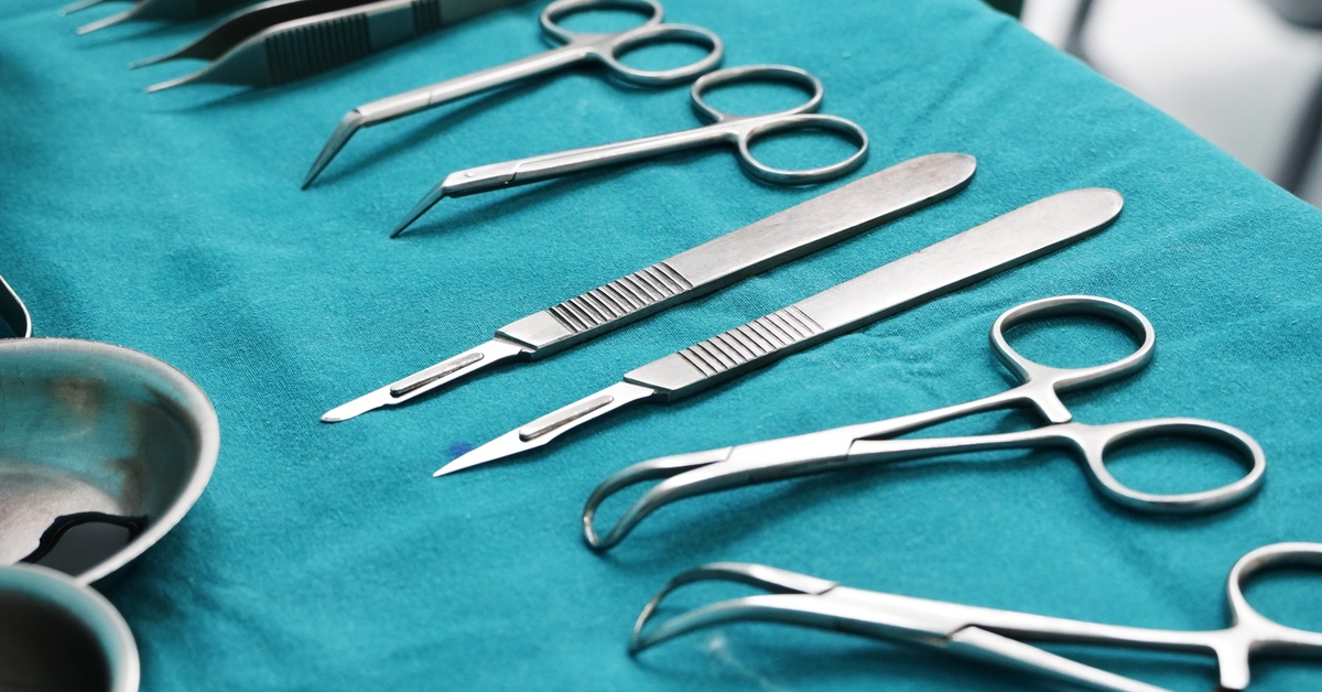 There are several kinds of tools laid out on a table. Some are scissors while others are scalpels.