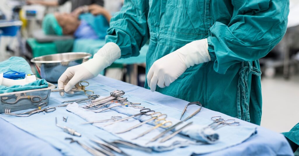 A person in medical garb is standing before a table; the table is filled with various medical tools.
