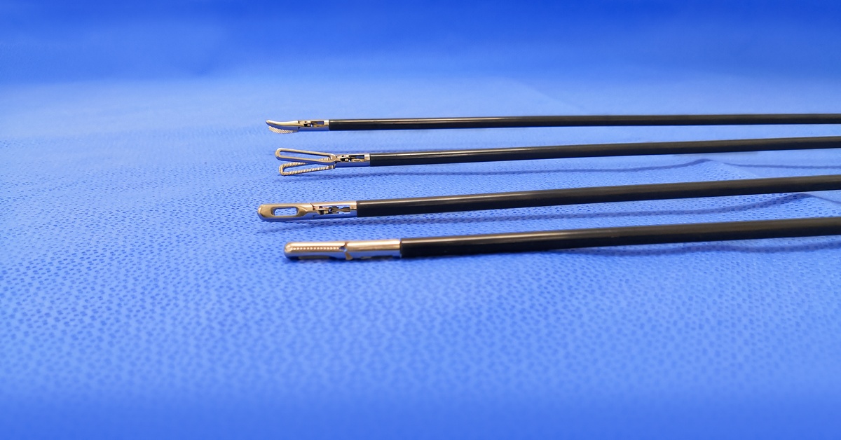 Laparoscopic surgical instrument tips are on a blue sterile drape. Their ends include loops, hooks, and rounded tips.